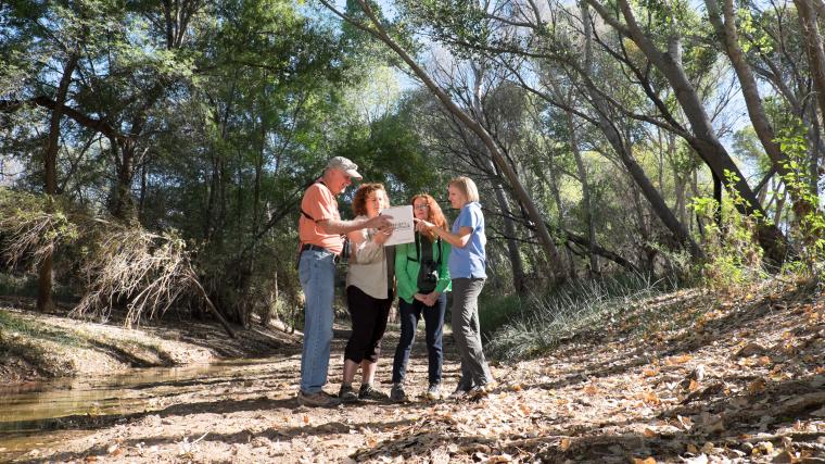 Four observers look at a clipboard in the field